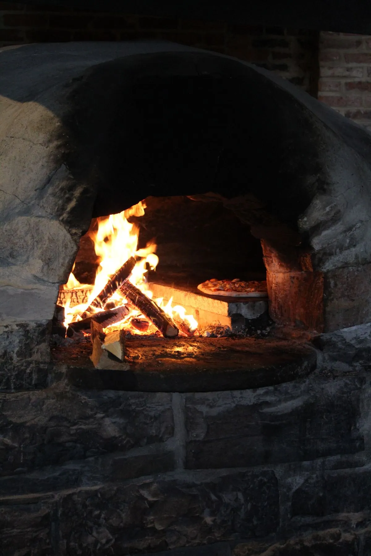 Pizzaiolo préparant des pizzas au feu de bois lors d'un mariage champêtre en plein air